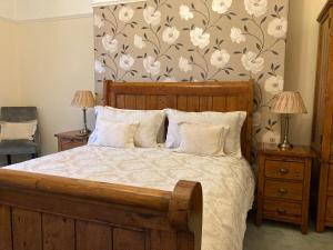 a bedroom with a wooden bed with white flowers on a wall at The Corner House Bed & Breakfast in Whitehaven