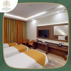 a hotel room with two beds and a flat screen tv at Emaar International in Mecca