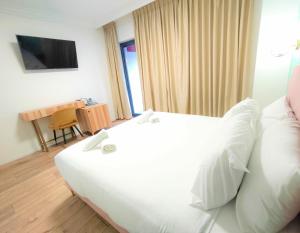 um quarto de hotel com uma cama branca e uma mesa em La Perle Hotel em Jerusalém