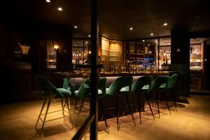 a bar with green chairs and a bar counter at Hotel Lowietje Lisse - Keukenhof in Lisse