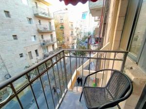 a chair on a balcony with a view of a street at La Perle Hotel in Jerusalem