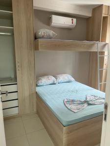 a small room with a bunk bed with blue sheets at Apes Enseada Guarujá in Guarujá