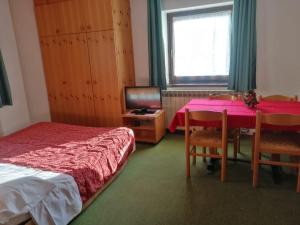 Un dormitorio con una cama, una mesa y un televisor. en Residence Hotel 4s Montagna, en Cogolo 10 fotos más