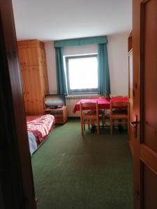 Habitación con mesa, cama y ventana en Residence Hotel 4s Montagna, en Cogolo