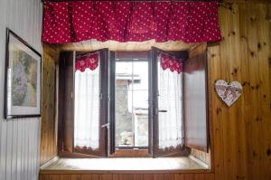 una ventana en una habitación con una cortina roja en Maison Rhémy - Relax e montagne, en Saint-Rhémy-en-Bosses