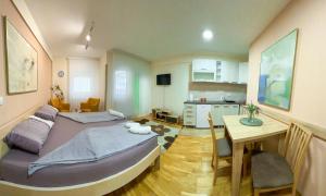 a bedroom with two beds and a table and a kitchen at Paspalj apartman in Novi Pazar