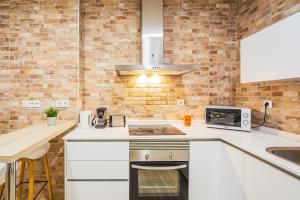 a kitchen with white cabinets and a brick wall at CartagenaFlats - Apartamentos Turísticos Jabonerías 16, CITY CENTER in Cartagena