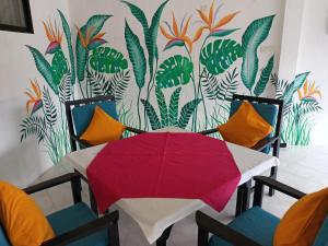 a table with a red umbrella in front of a mural at Aprima Hotel in Kalutara