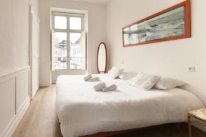 een witte slaapkamer met 2 bedden en een groot raam bij Le Joffre - sur le port - wifi in Vannes