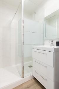 een witte badkamer met een douche en een wastafel bij Le Joffre - sur le port - wifi in Vannes