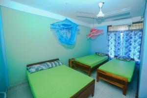 two twin beds in a room with blue walls at Tony's Garden House Back Packers inn in Jaffna