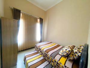 two beds in a small room with a window at Vila Diamond Batu in Songgoriti