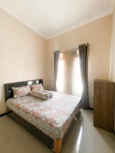 a bedroom with a bed and a window with curtains at Vila Diamond Batu in Songgoriti