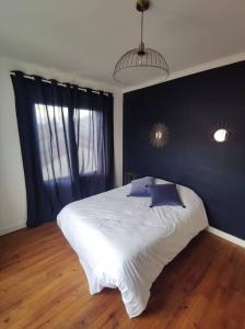 ein Schlafzimmer mit einem weißen Bett und einer blauen Wand in der Unterkunft villa_lumiere_la_rochelle avec spa à 800m de l'océan in La Rochelle