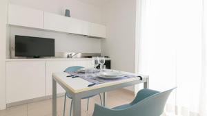 a white kitchen with a table with chairs and a tv at Residenza Excelsior - Bilocali Piano Terra in Marina di Montenero