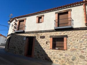 un edificio de piedra con ventanas con barrotes y una puerta en Casa rural las pelliquerinas, en Almoharín