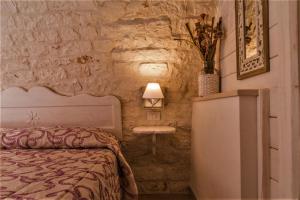 um quarto com uma cama e uma parede de pedra em B&B Trulli Donna Isabella em Locorotondo