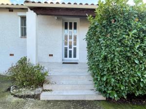 una casa blanca con una puerta y escaleras delante en Maison d'une chambre avec piscine privee jardin clos et wifi a La Calmette, en La Calmette