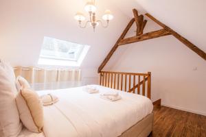 a bedroom with a white bed with a chandelier at La Coquette - Tout confort - 100m du Canal - Calme - Wifi in Malestroit
