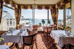 um restaurante com mesas e cadeiras e janelas grandes em Panorama Guest House em Saint Aubin