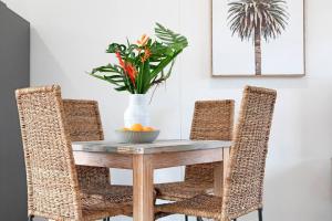 a dining room table with two chairs and a vase with flowers at 'Botanica Aguila' Chic Nightcliff Balcony Pad in Nightcliff