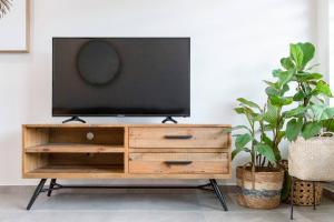 a television on top of a wooden dresser in a living room at 'Botanica Aguila' Chic Nightcliff Balcony Pad in Nightcliff