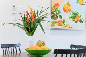 a table with a bowl of fruit and a vase with a plant at 'Botanica Paradiso' A Vibrant Nightcliff Solace in Nightcliff