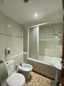 a bathroom with a toilet and a tub and a sink at HOSTAL GALICIA CARDEDEU in Cardedeu