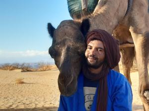Un uomo in piedi accanto a un cammello nel deserto di Sahara Peace camp a Zagora
