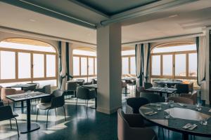 a restaurant with tables and chairs and windows at Hotel San Luca in Cortona