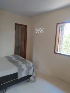 um quarto com uma cama num quarto com uma janela em Kitnete Aconchegante em Itacaré