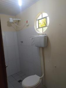 a small bathroom with a toilet and a window at Kitnete Aconchegante in Itacaré