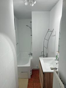 un bagno bianco con vasca e lavandino di Appartement centre ville a Tournai