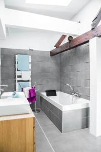 een badkamer met een groot bad en een wastafel bij L'Appartement des Artistes avec Terrasse in Kaysersberg