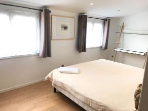 een slaapkamer met een wit bed en 2 ramen bij L'Appartement des Artistes avec Terrasse in Kaysersberg