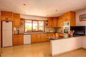 a large kitchen with wooden cabinets and a white refrigerator at Can Lari Chalet in Vall-Llobrega