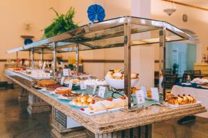 uma linha de buffet com vários produtos de pastelaria e outros alimentos em Hotel Minas Gerais em Poços de Caldas