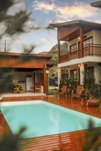 a house with a swimming pool in front of a house at Pousada Rosa Maria in Praia do Rosa