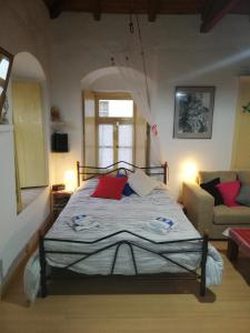 a bedroom with a bed with red pillows and a couch at Au pied de la falaise rouge in Leonidion