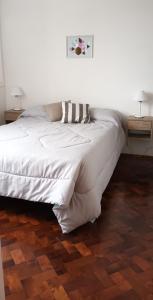 1 dormitorio con 1 cama blanca y 2 mesitas de noche en DEPARTAMENTO PARQUE ESPAÑA en Rosario