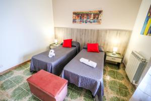 two beds in a small room with red pillows at B&B Giardino dei Cedri in Trabia