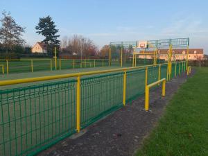 a fence with yellow poles and a basketball hoop at Zénithouse in Éterville