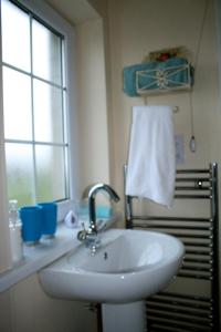 baño con lavabo, ventana y toalla en Ballyharvey B&B en Antrim