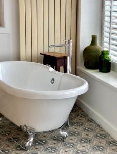 a white bath tub in a bathroom with a vase at Harbour View House in St Ives