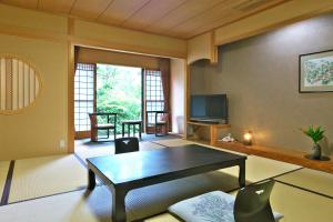 Yuraku Hotel في Awara: غرفة معيشة مع طاولة وتلفزيون