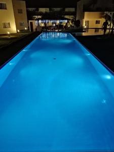 a blue swimming pool at night with lights at Chalet no paraíso in Maracajaú