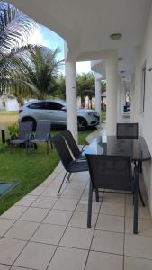 een patio met stoelen, een tafel en een auto bij Chalet no paraíso in Maracajaú