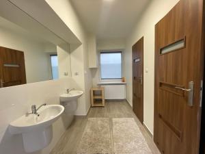 łazienka z 2 umywalkami i drewnianymi drzwiami w obiekcie Apartamenty Trzciana w mieście Rzeszów
