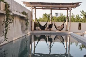 a swimming pool with two hammocks hanging from a pergola at Boutique Hotel EL NIDO Holbox in Holbox Island