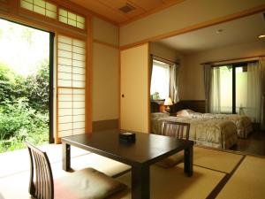 a room with a table and a room with two beds at Ryokan Kutsuroginoya Yuu in Takayama
